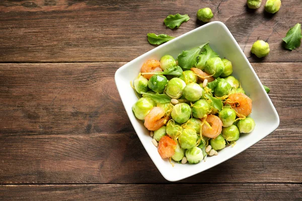 Ciotola di deliziosa insalata con cavoletti di Bruxelles e gamberetti su tavolo di legno, vista dall'alto. Spazio per testo — Foto Stock