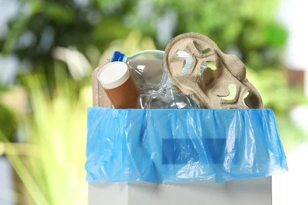Trash bin with garbage on blurred background. Recycling problem — Stock Photo, Image