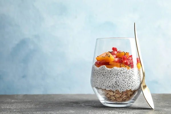 Copo de saboroso pudim de semente de chia com granola, cáqui e romã na mesa, espaço para texto — Fotografia de Stock