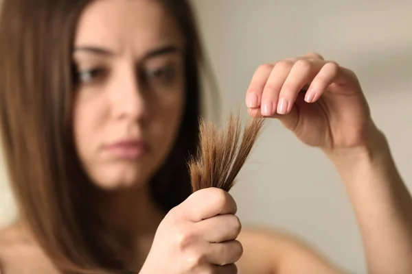 Mujer con el pelo dañado sobre fondo borroso, enfoque selectivo. Puntas partidas — Foto de Stock