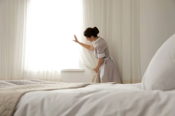 若いメイドホテルの部屋でカーテンを開ける — ストック写真