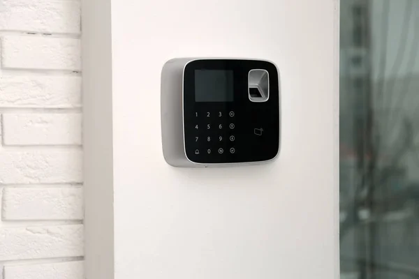 Modern alarm system with fingerprint scanner on white wall indoors Stock Photo