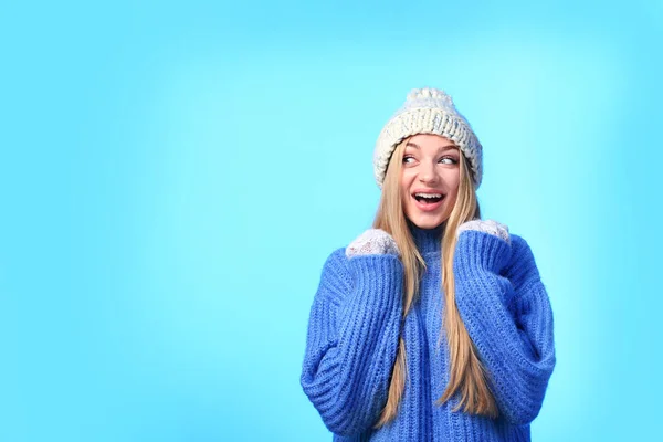 Portrait of emotional young woman in stylish hat, sweater and mittens on color background, space for text. Winter atmosphere Stock Image