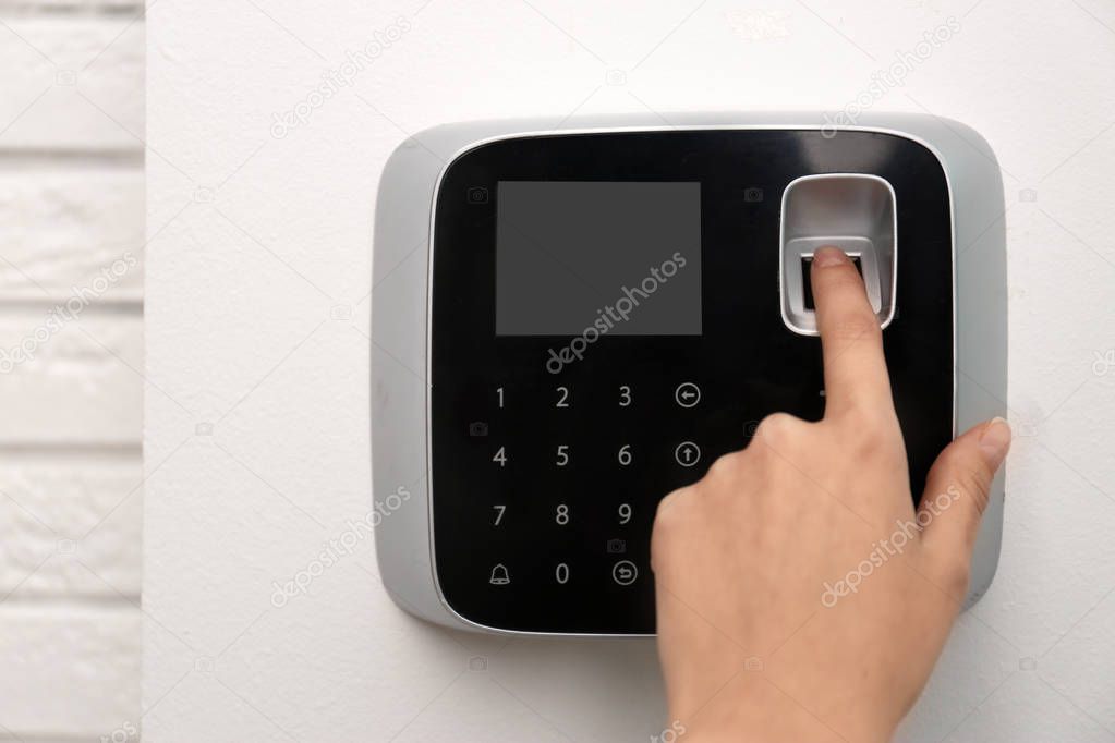 Woman scanning fingerprint on alarm system indoors, closeup