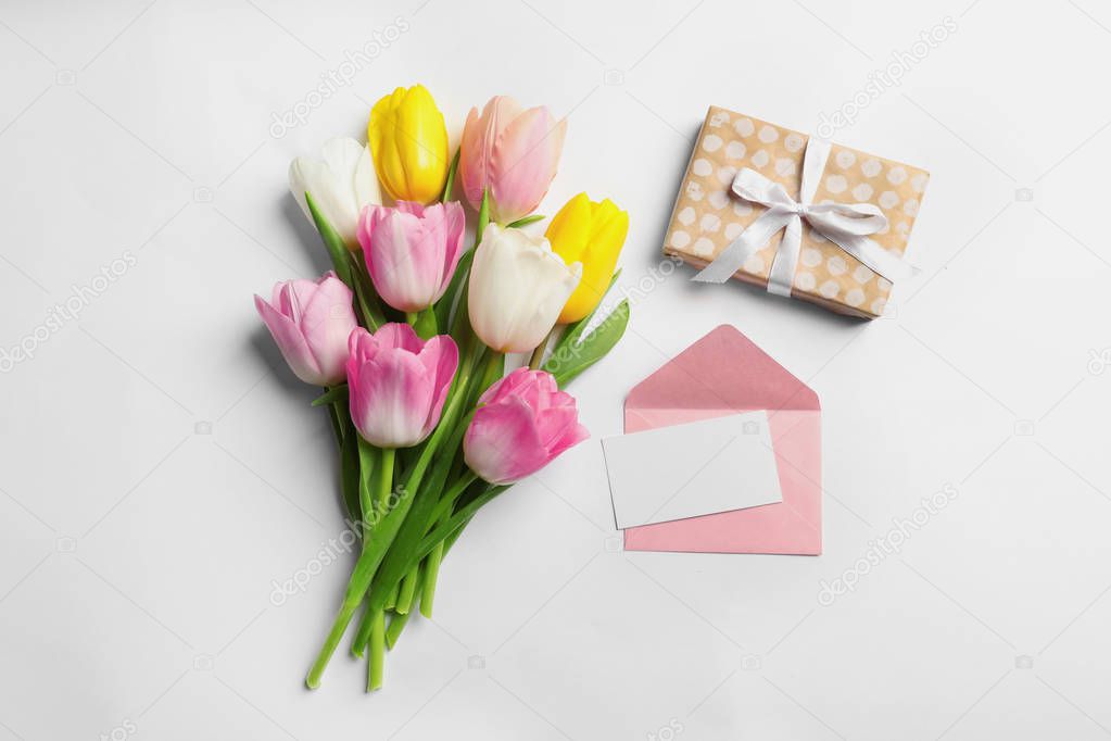 Flat lay composition of tulips and blank card on white background, space for text. International Women's Day