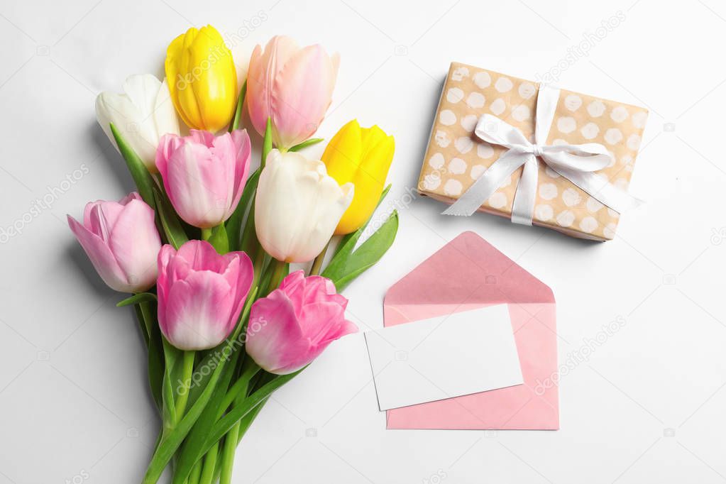 Flat lay composition of tulips and blank card on white background, space for text. International Women's Day