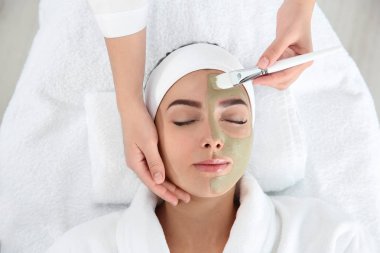 Spa Salonu, görünümünün üzerinde müşterinin yüzüne maske uygulayarak güzellik uzmanı