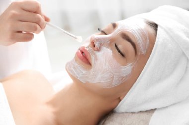 Spa salonu müşterinin yüzüne maske uygulayarak güzellik uzmanı