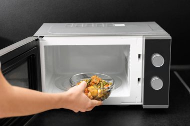 Mutfakta masada mikrodalga fırın kullanan genç kadın