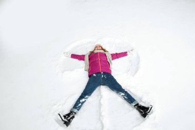 Beautiful woman making snow angel on winter day clipart