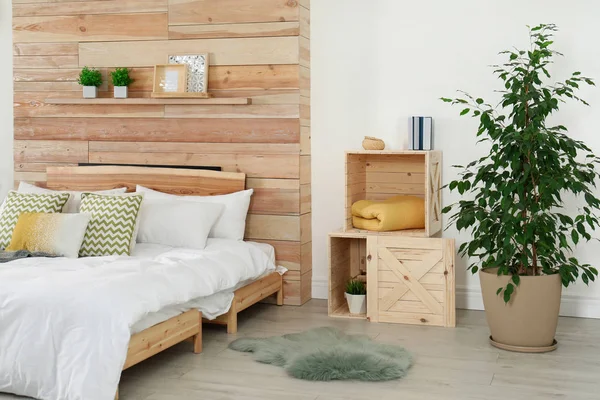 Quarto elegante interior com cama confortável perto da parede de madeira — Fotografia de Stock