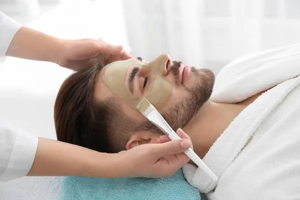 Cosmetologue appliquant un masque sur le visage du client dans le salon de spa — Photo