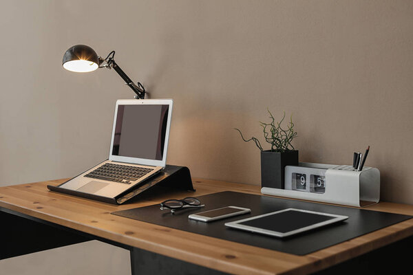 Современный интерьер рабочего места с ноутбуком и устройствами на столе. Пространство для текста
