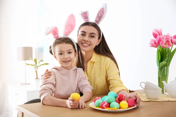 Mutter und Tochter mit Hasenohren Stirnbändern und bemalten Ostereiern zu Hause — Stockfoto