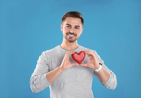 Hombre sosteniendo corazón decorativo sobre fondo de color — Foto de Stock