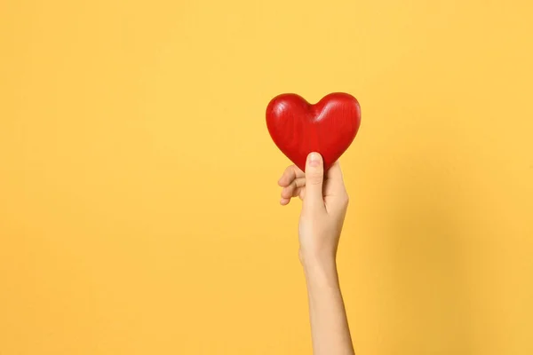 Mujer sosteniendo el corazón decorativo en la mano sobre fondo de color, espacio para el texto — Foto de Stock