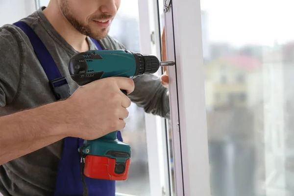 Trabalhador da construção usando broca durante a instalação de janela dentro de casa, close-up — Fotografia de Stock