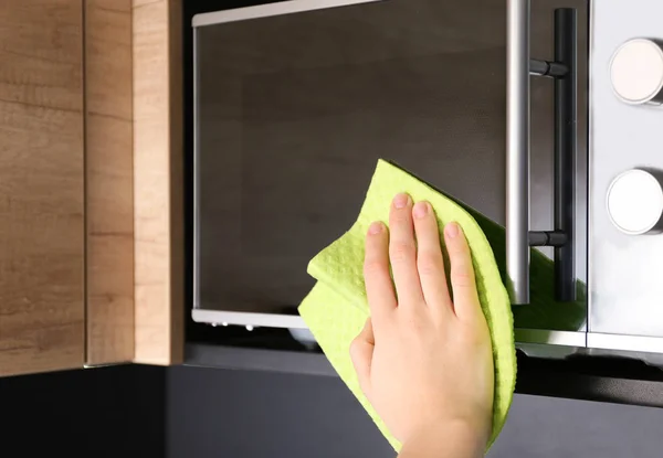 Woman cleaning microwave oven with rag in kitchen, closeup — Stock Photo, Image