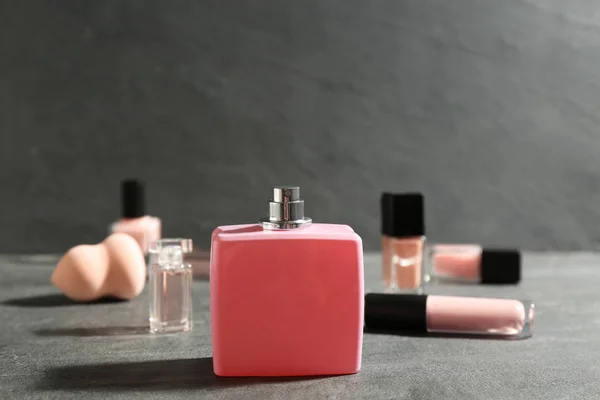 Flaska med parfym och kosmetika på grå bord — Stockfoto