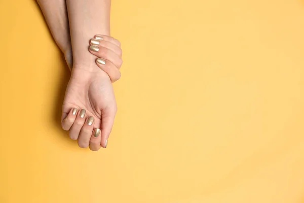 Mujer mostrando manicura dorada sobre fondo de color, vista superior con espacio para texto. Tendencias de esmalte de uñas — Foto de Stock