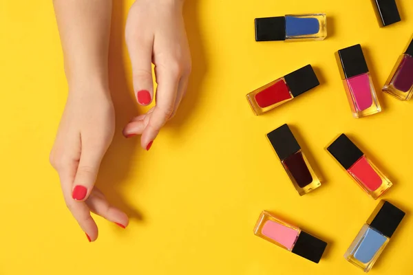 Woman with red manicure and nail polish bottles on color background, top view — Stock Photo, Image