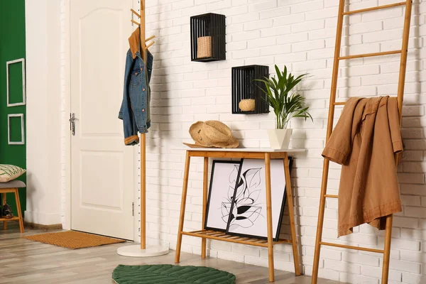 Stylish hallway interior with hanger stand, table and decorative wooden ladder