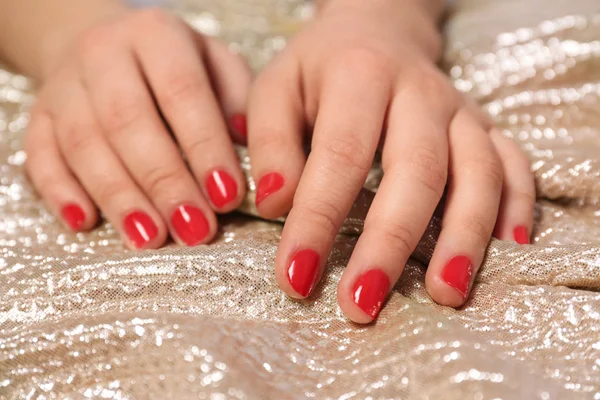 Woman with red manicure on gold fabric, closeup. Nail polish trends — Stock Photo, Image