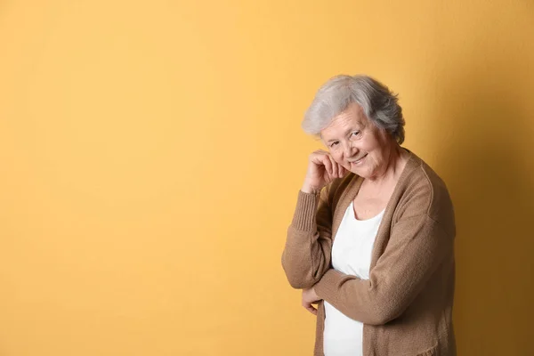 Portret van een grootmoeder in stijlvolle kleding op kleur achtergrond, ruimte voor tekst — Stockfoto