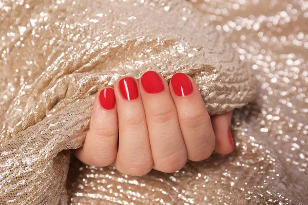 Woman with red manicure holding gold fabric, closeup. Nail polish trends — Stock Photo, Image