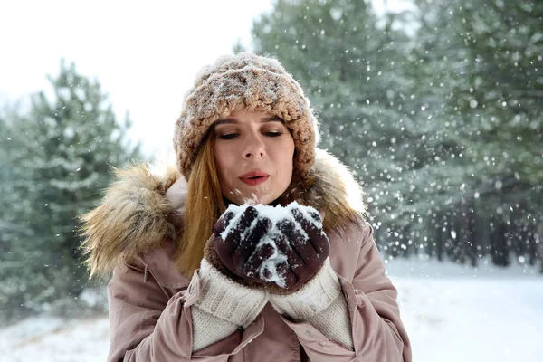 Hermosa mujer soplando nieve en el bosque de invierno — Foto de Stock