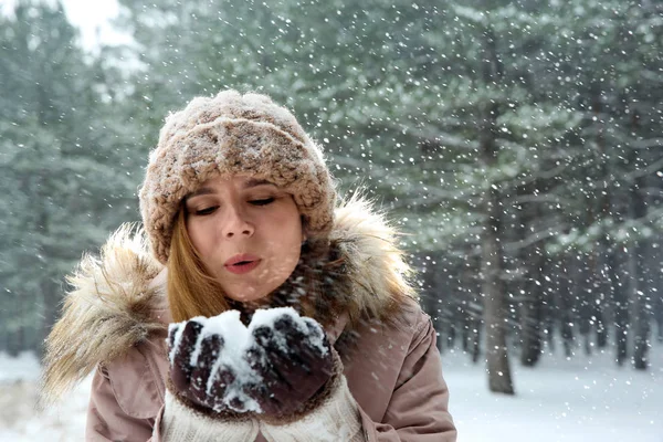 Hermosa mujer soplando nieve en el bosque de invierno. Espacio para texto —  Fotos de Stock