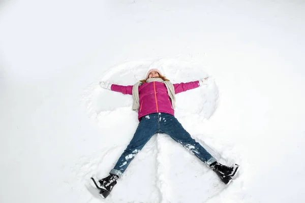 Hermosa mujer haciendo ángel de nieve en el día de invierno — Foto de Stock