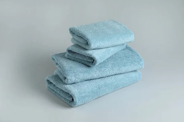 Στοίβα από φρέσκο αφράτες πετσέτες σε γκρίζο φόντο — Φωτογραφία Αρχείου