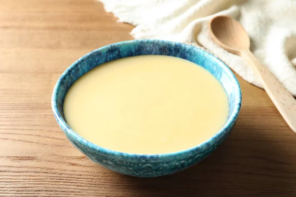 Tigela com leite condensado na mesa de madeira. Produtos lácteos — Fotografia de Stock