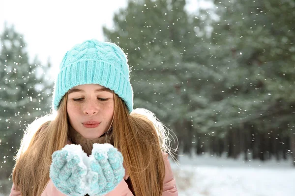 Adolescente menina soprando neve na floresta de inverno. Espaço para texto — Fotografia de Stock