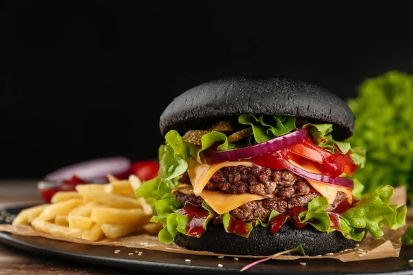 Deska s černým burger a hranolky na stole. Prostor pro text — Stock fotografie