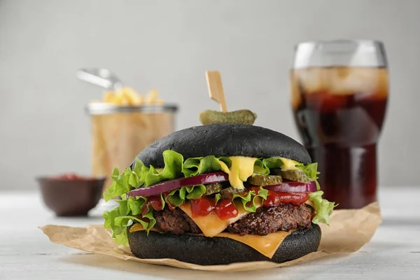 Smaczne burger czarny, podawane z frytkami i cola na stole — Zdjęcie stockowe