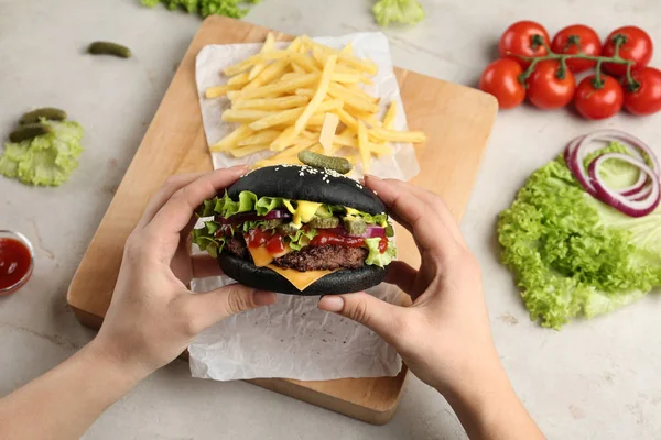 Siyah burger hizmet masada, closeup tutan kadın — Stok fotoğraf