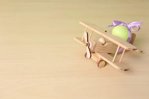 Деревянный самолет с милым пасхальным яйцом на столе, место для текста — стоковое фото