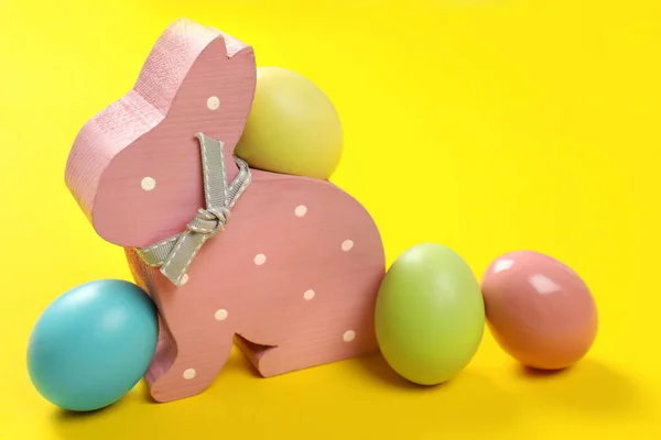 可爱的木复活节兔子和染色鸡蛋在颜色背景 — 图库照片