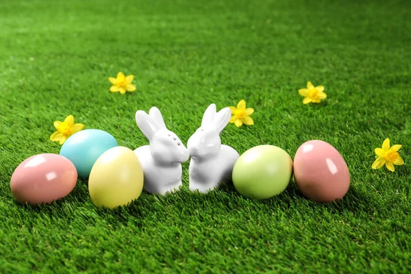 Keramická velikonoční zajíčky a barvená vejce na zelené trávě — Stock fotografie