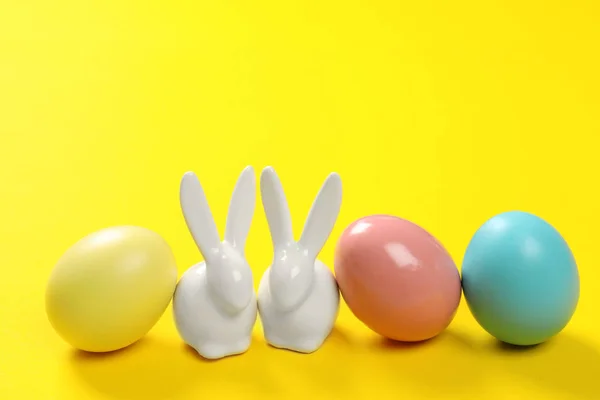 陶瓷复活节兔子和染色蛋在颜色背景 — 图库照片