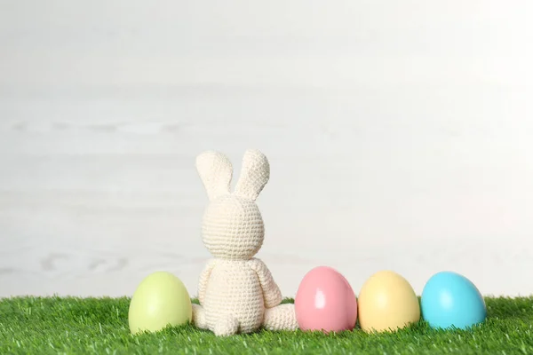 Cute Easter bunny toy and dyed eggs on green grass, space for text — Stock Photo, Image