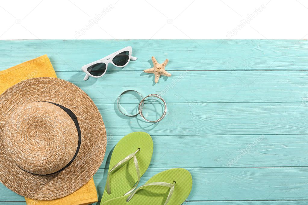 Flat lay composition with beach accessories on wooden background. Space for text