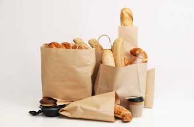 Beyaz arka plan üzerinde kağıt torbalarda farklı taze ekmek yapım ürünleri