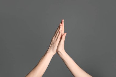 Gri arka plan, closeup yüksek beş veren kadın. Zafer kavramı