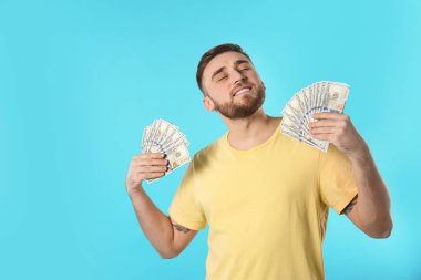 Mutlu genç adam kendini renk arka plan üzerinde para ile fanning. Metin için yer