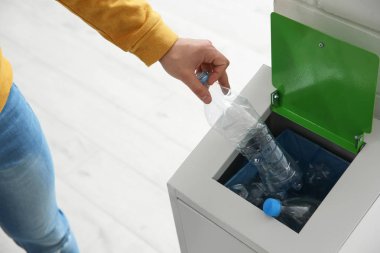 Genç adam bin ve metal kapalı, closeup boş plastik şişe atma. Atık geri dönüşüm