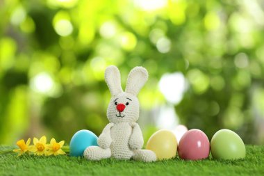 Sevimli Paskalya bunny oyuncak ve bulanık arka plan, metin için yer yeşil çimenlerin üzerinde boyalı yumurta