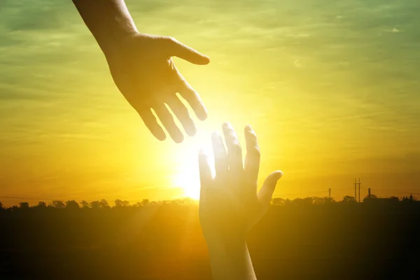 Kadın eli için açık havada, güneş doğarken closeup ulaşan adam. Kavram — Stok fotoğraf
